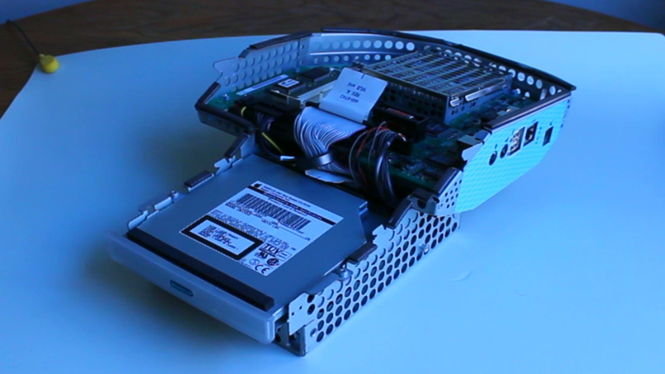 The internal chassis of an iMac G3 separated from its screen and case: mostly a CD drive, a circuit board, and a bundle of cables connecting the two